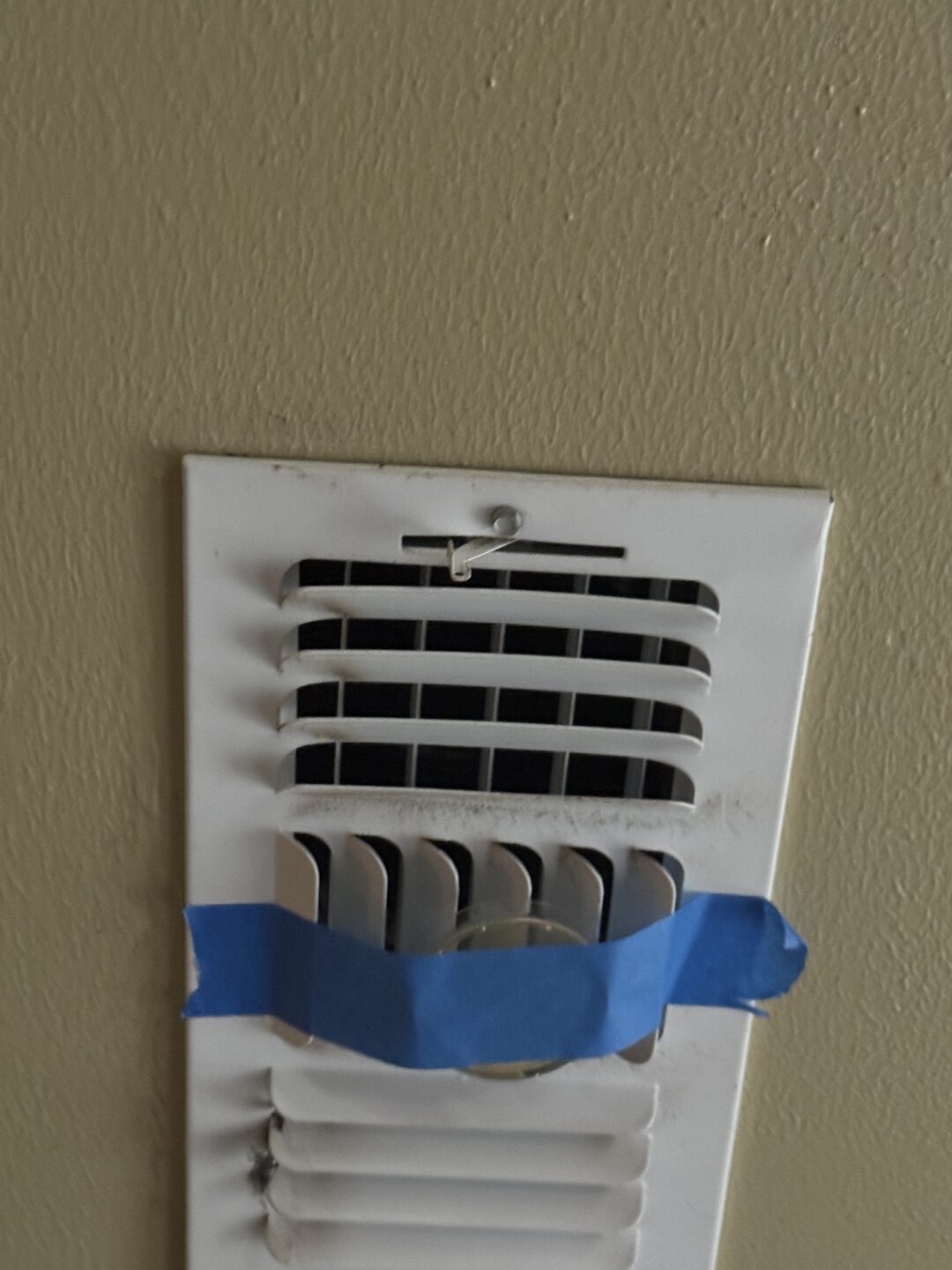 An open petri plate taped across a ceiling supply grille so conditioned air passes over it