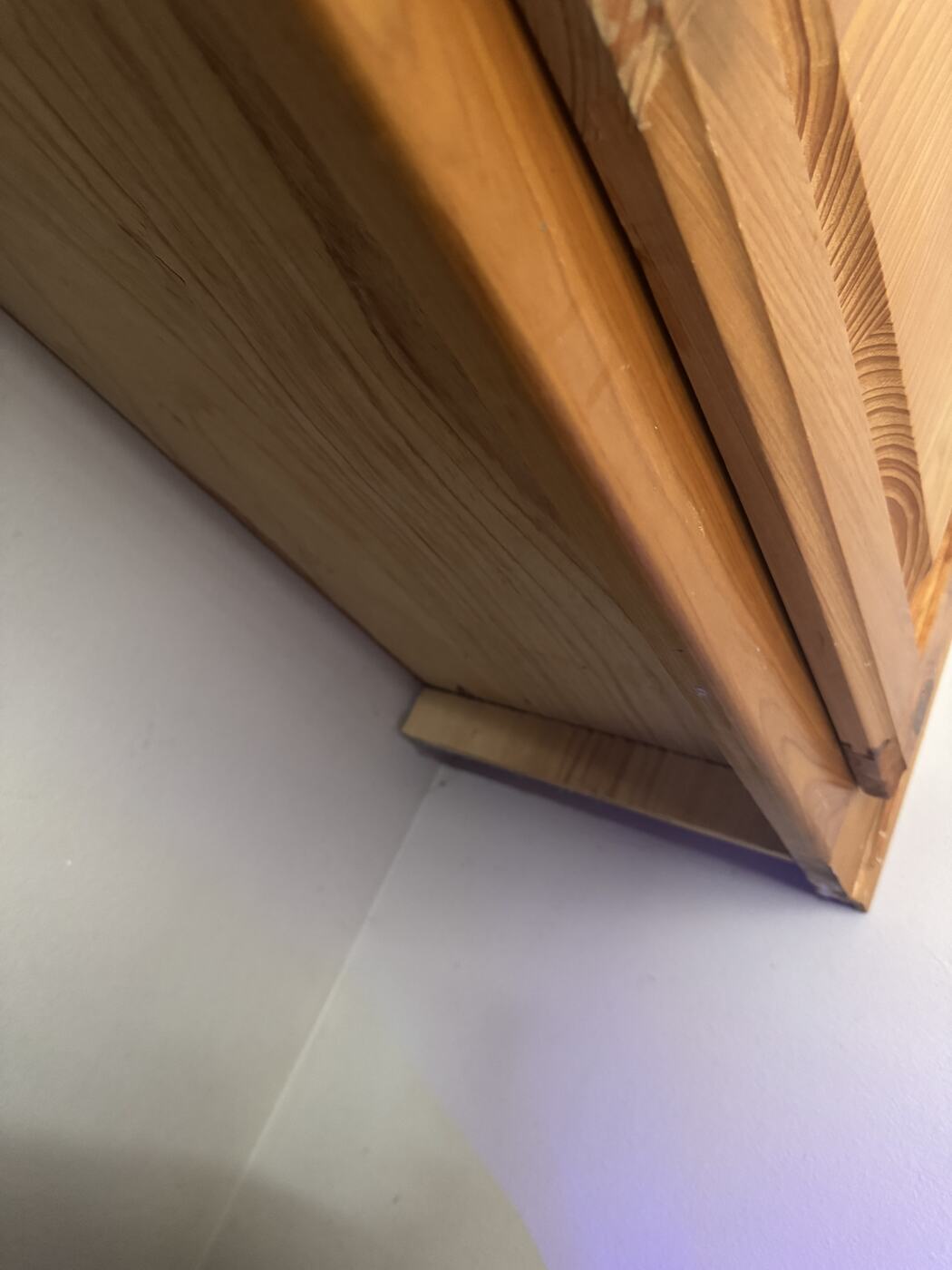 The underside of a laundry room cabinet photographed in normal light, appearing to be clean bare wood