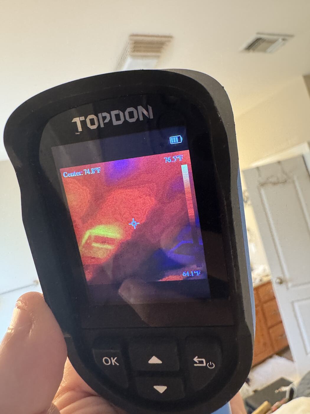 A thermal camera image of a ceiling beside an air vent, showing warm and cooler zones, with the vent visible in the room behind