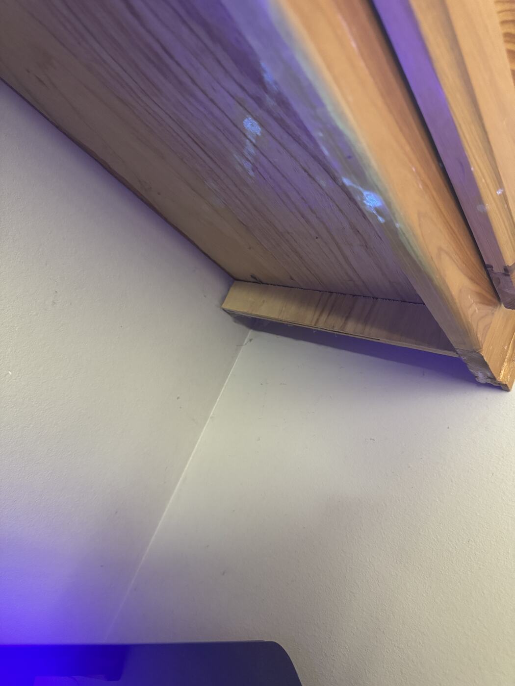 The same underside of the cabinet photographed under ultraviolet light, showing pale patches that fluoresce